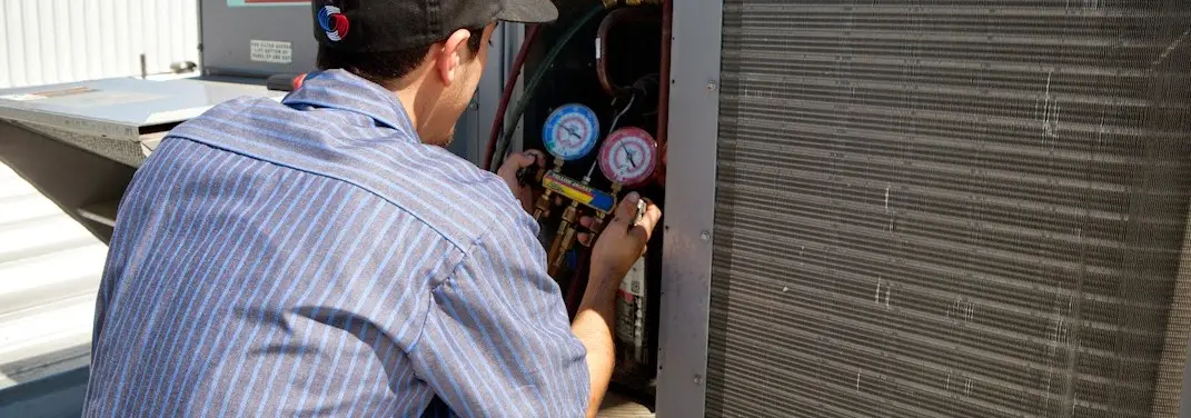 HVAC technician servicing a condenser unit in Bacliff